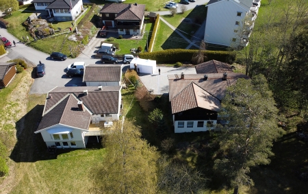 Dronebilde av Tom Hagens eiendom i Lørenskog (til høyre i bildet). Tirsdag ble det satt opp et telt over en kum ved innkjørselen til huset.